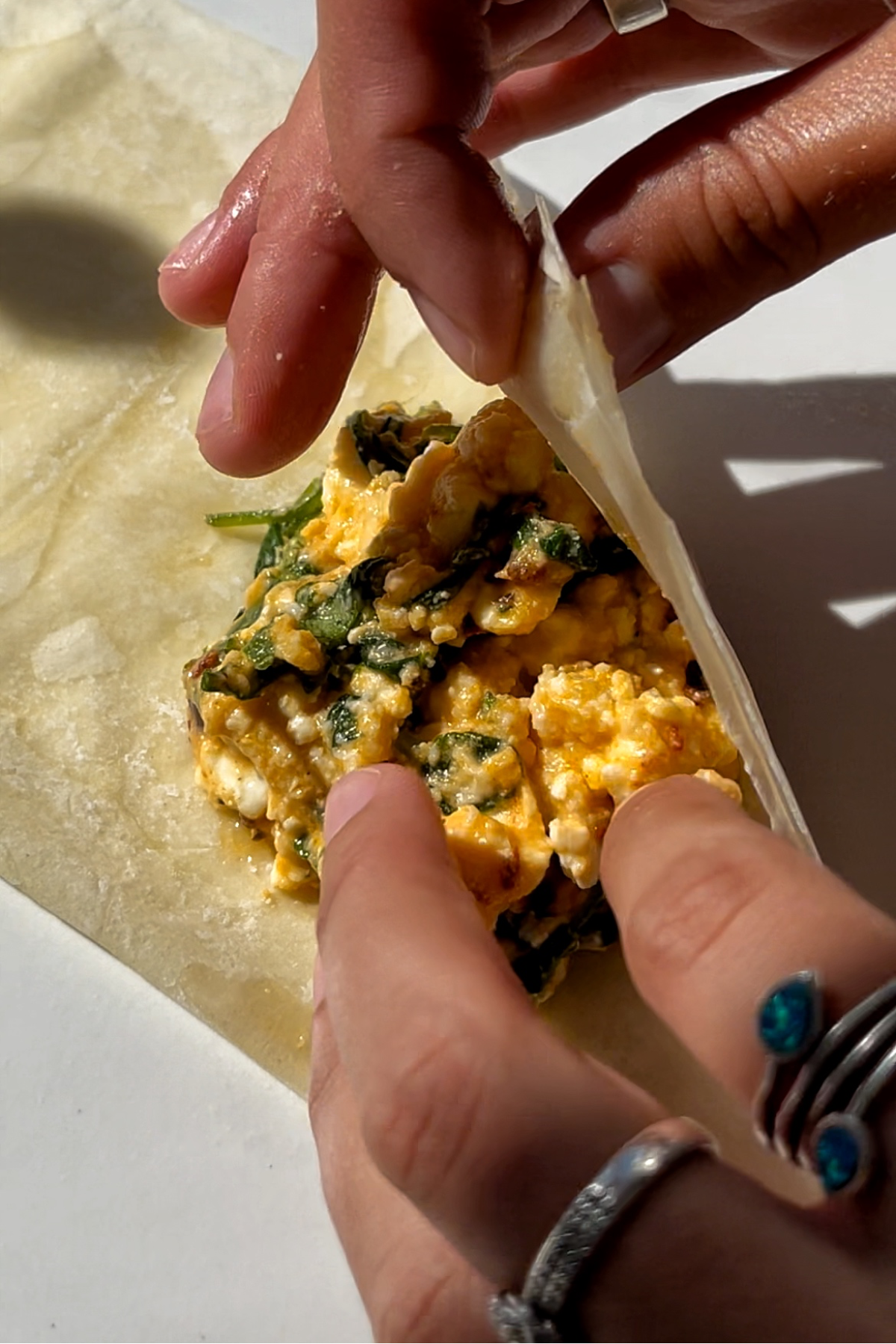 Folding up a filo pastry with filling inside.