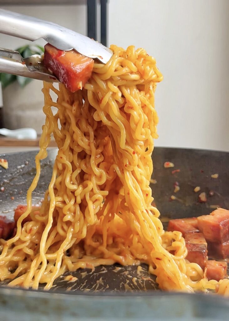 Spam ramen noodles being pulled out of a pan