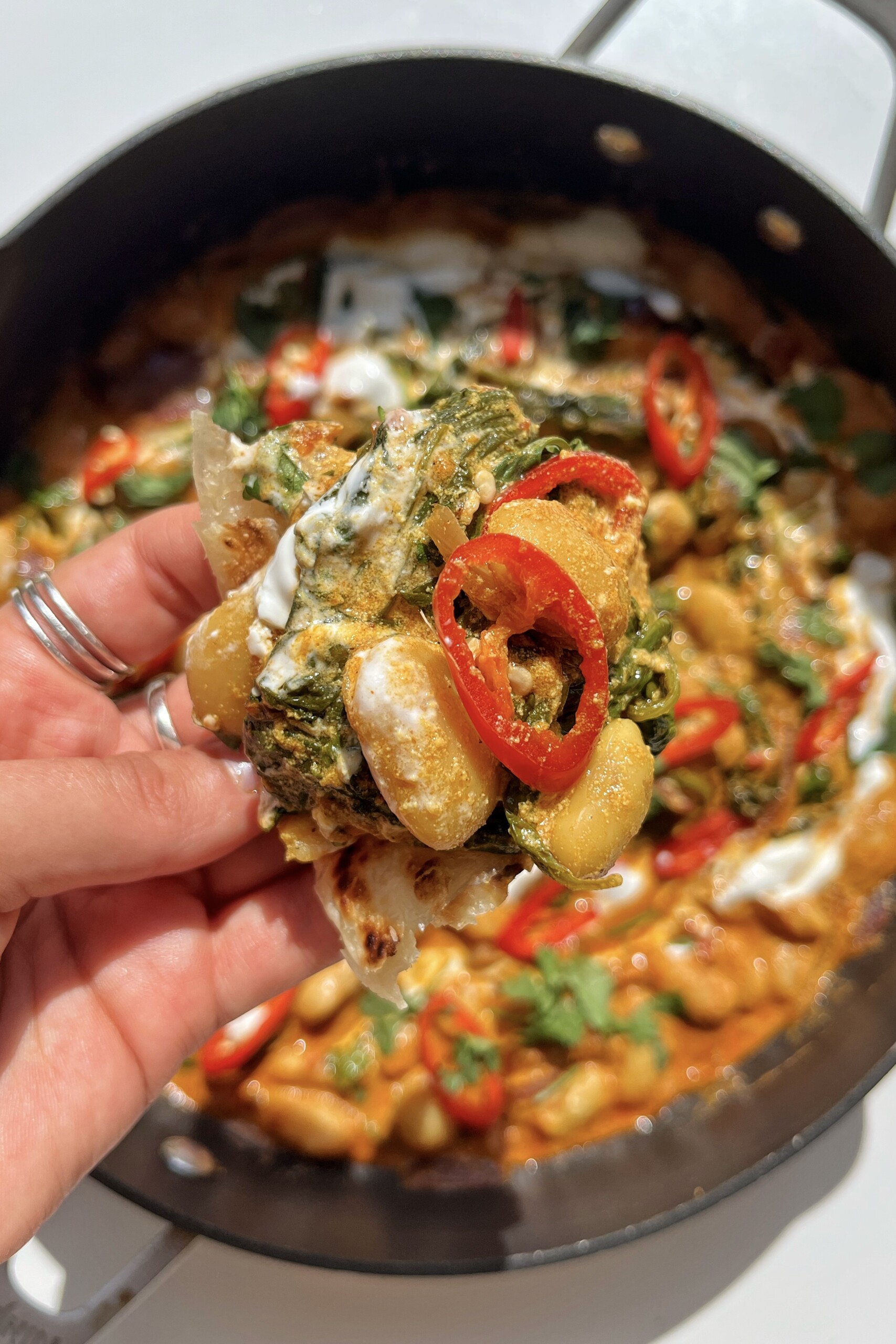 spicy bean curry with spinach held in girls hand.