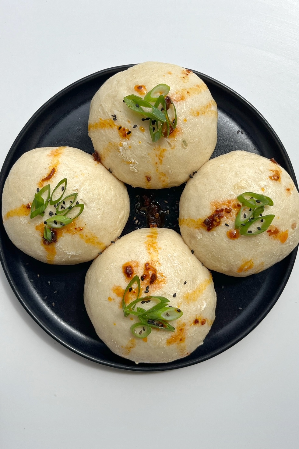 coconut bao (steamed buns) topped with spring onion and chilli oil.