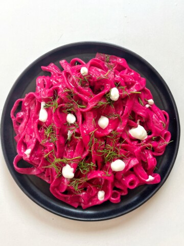 Pink pasta on a black plate.