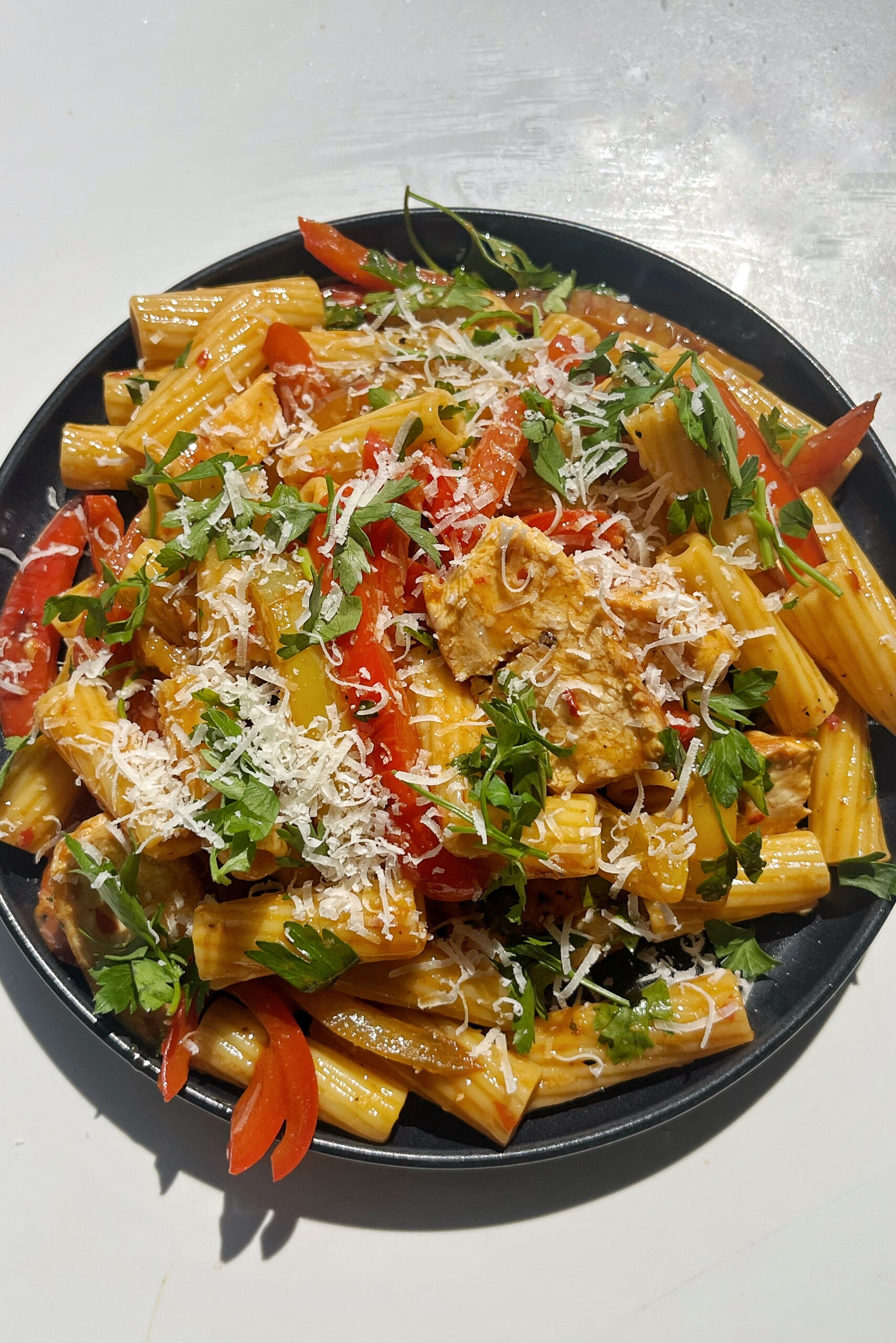 Pollo picante pasta on a black plate.