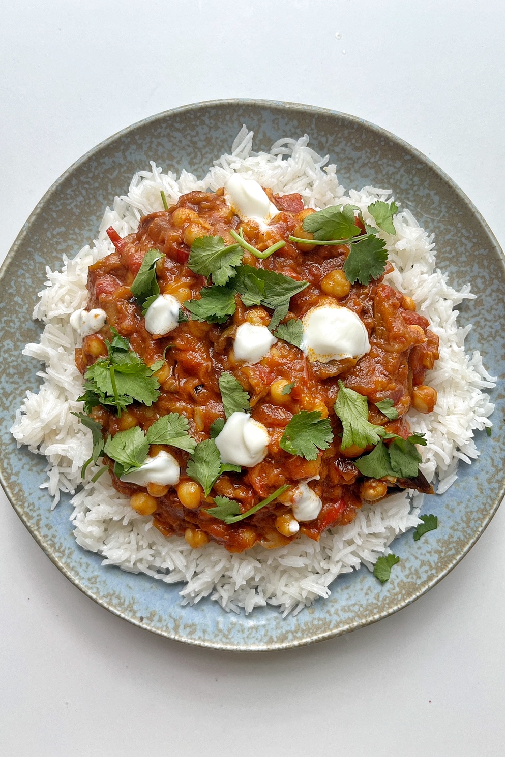 Aubergine tikka masala on blue plate.