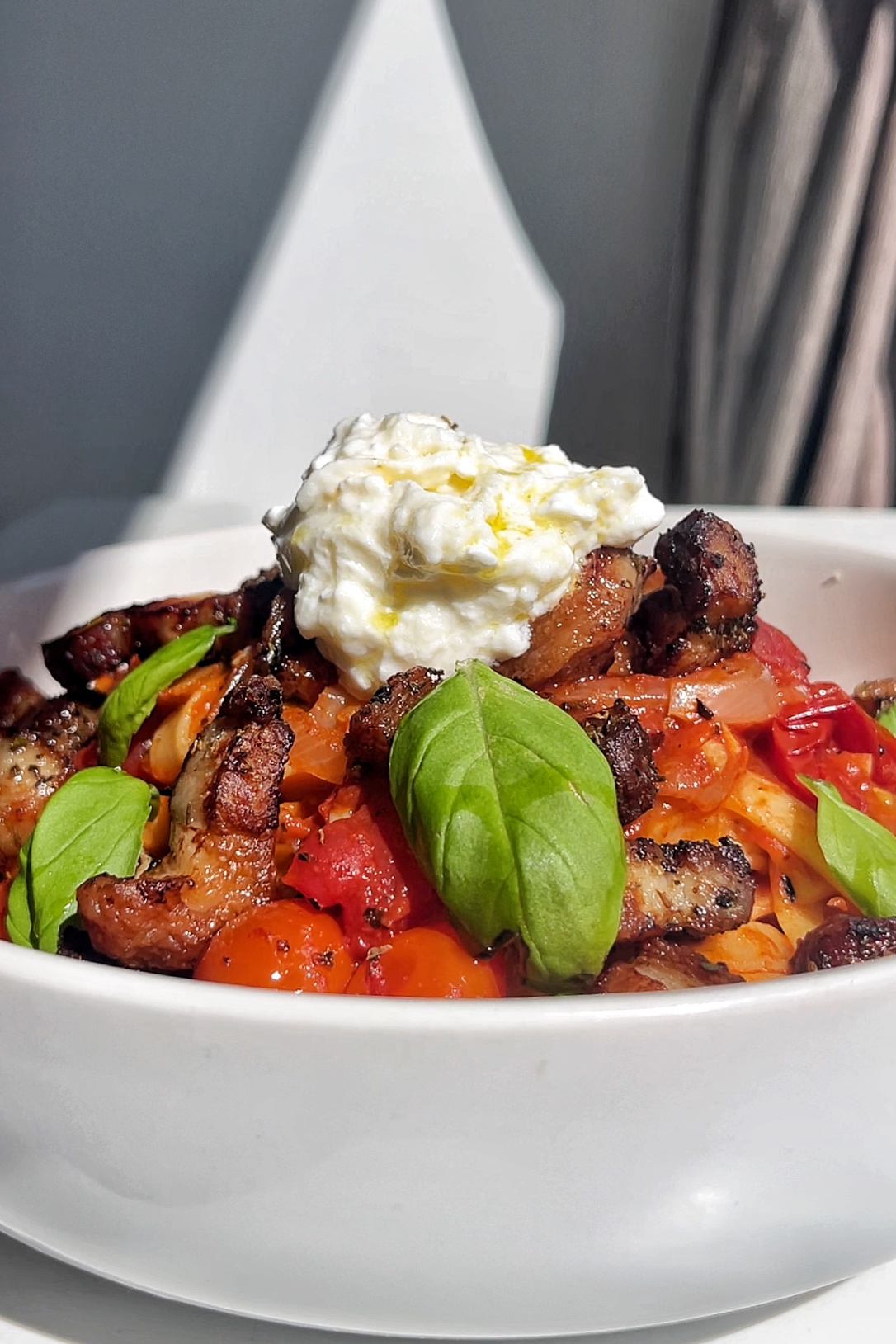 white bowl containing pork belly with roasted vegetables topped with cottage cheese.