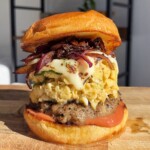 Scrambled Egg Burger with a sausage patty, caramelised onions, and melted cheese.