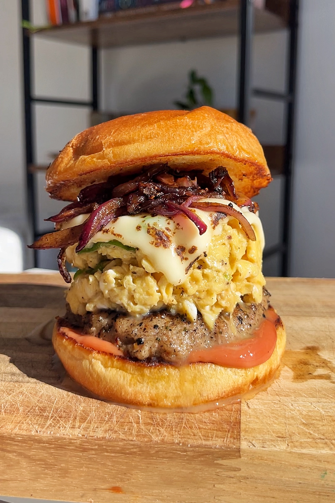 Scrambled Egg Burger with a sausage patty, caramelised onions, and melted cheese.