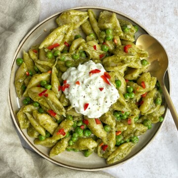White background with a plate of green pasta.