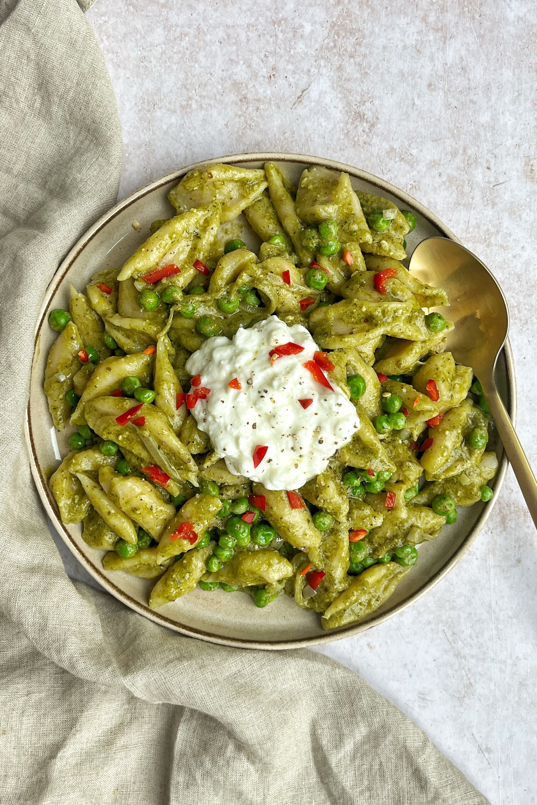 White background with a plate of green pasta.