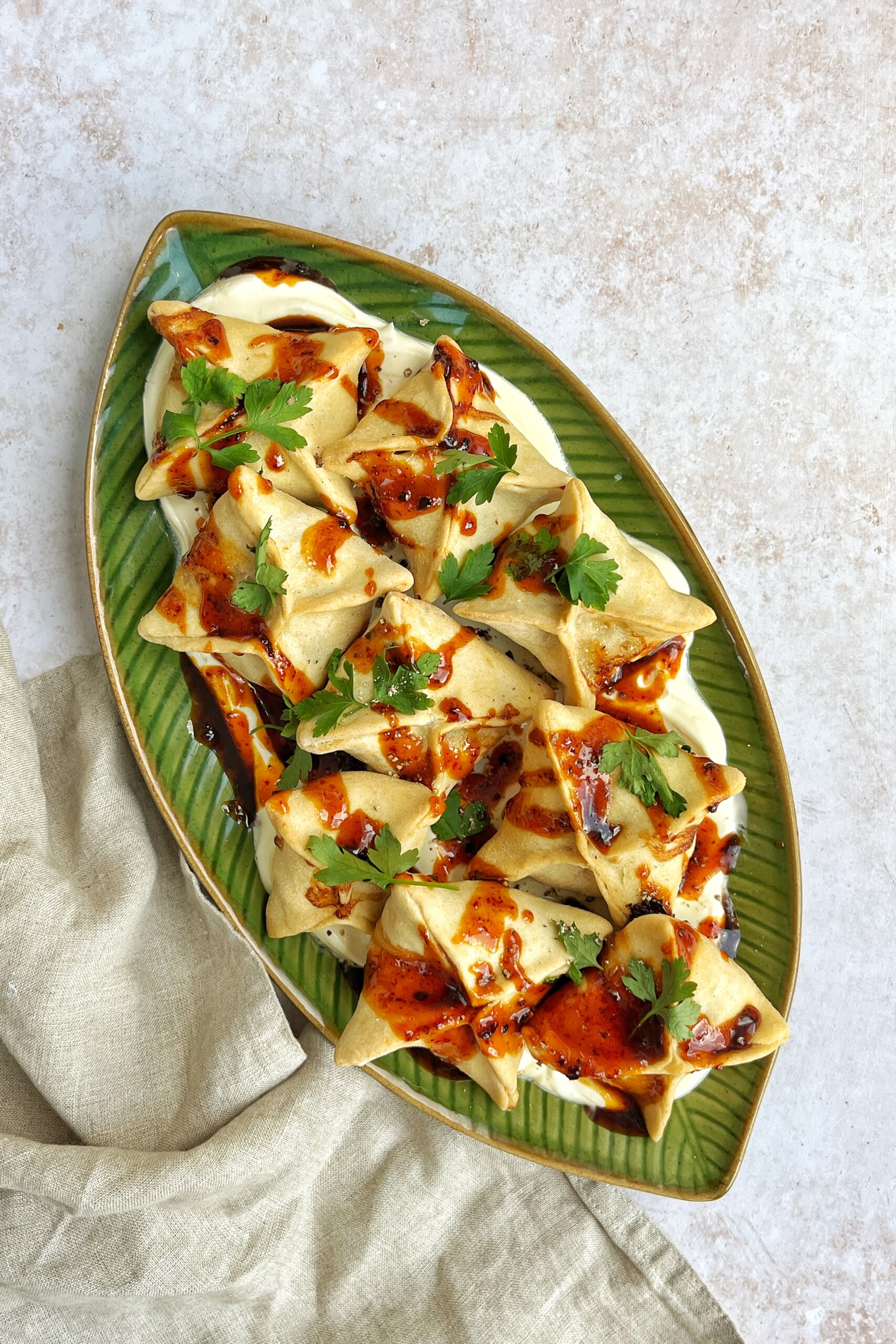 Shot of honey harissa sausage dumplings on green plate with cream cloth.