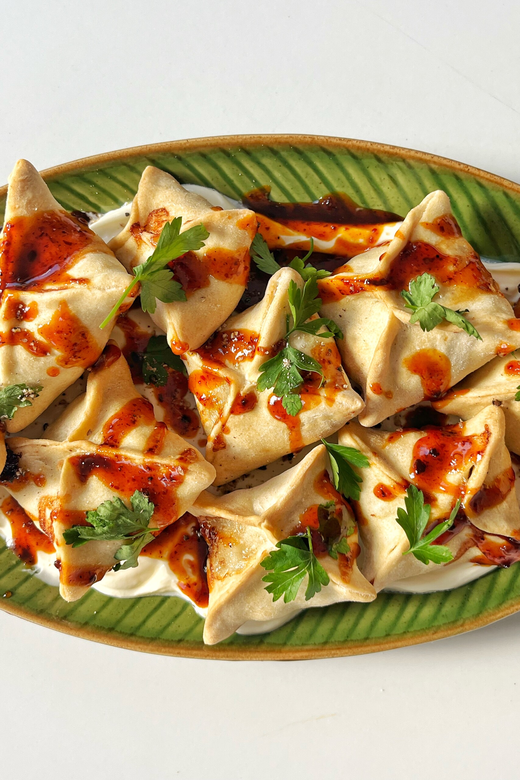 Honey harissa sausage dumplings on a green plate.