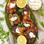 Air fryer greek yogurt chicken on a green plate with lemons.