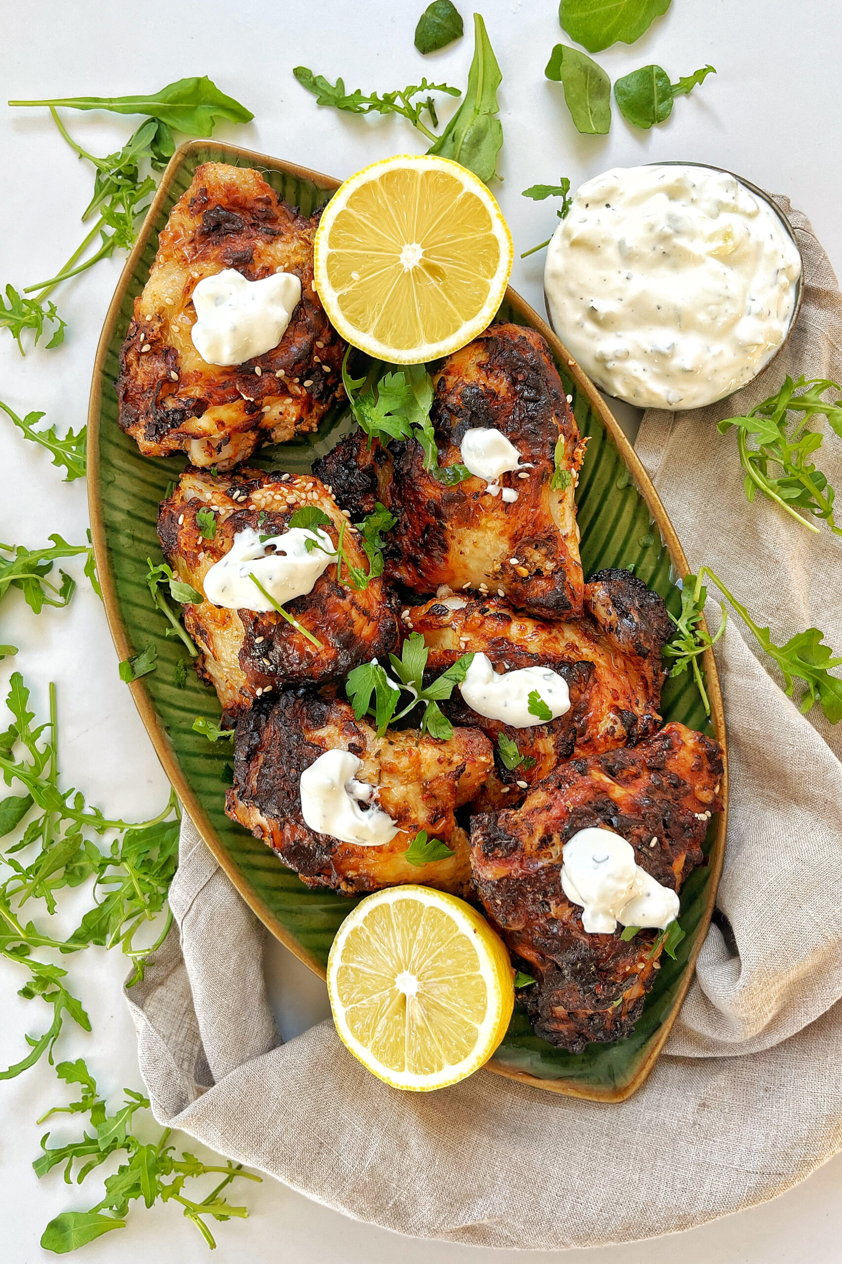 Air fryer greek yogurt chicken on a green plate with lemons.