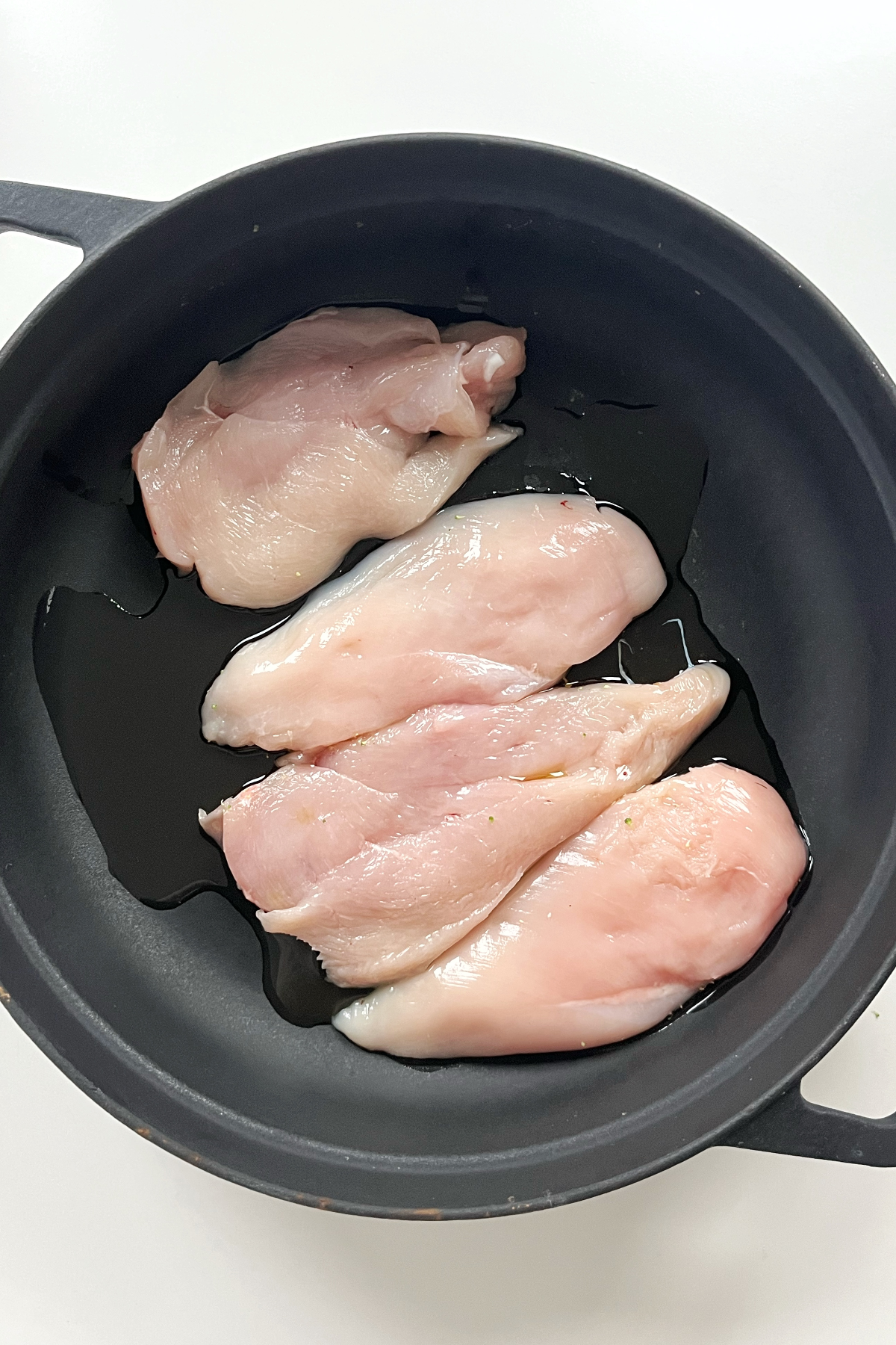 Black pan with 4 pieces of chicken inside.