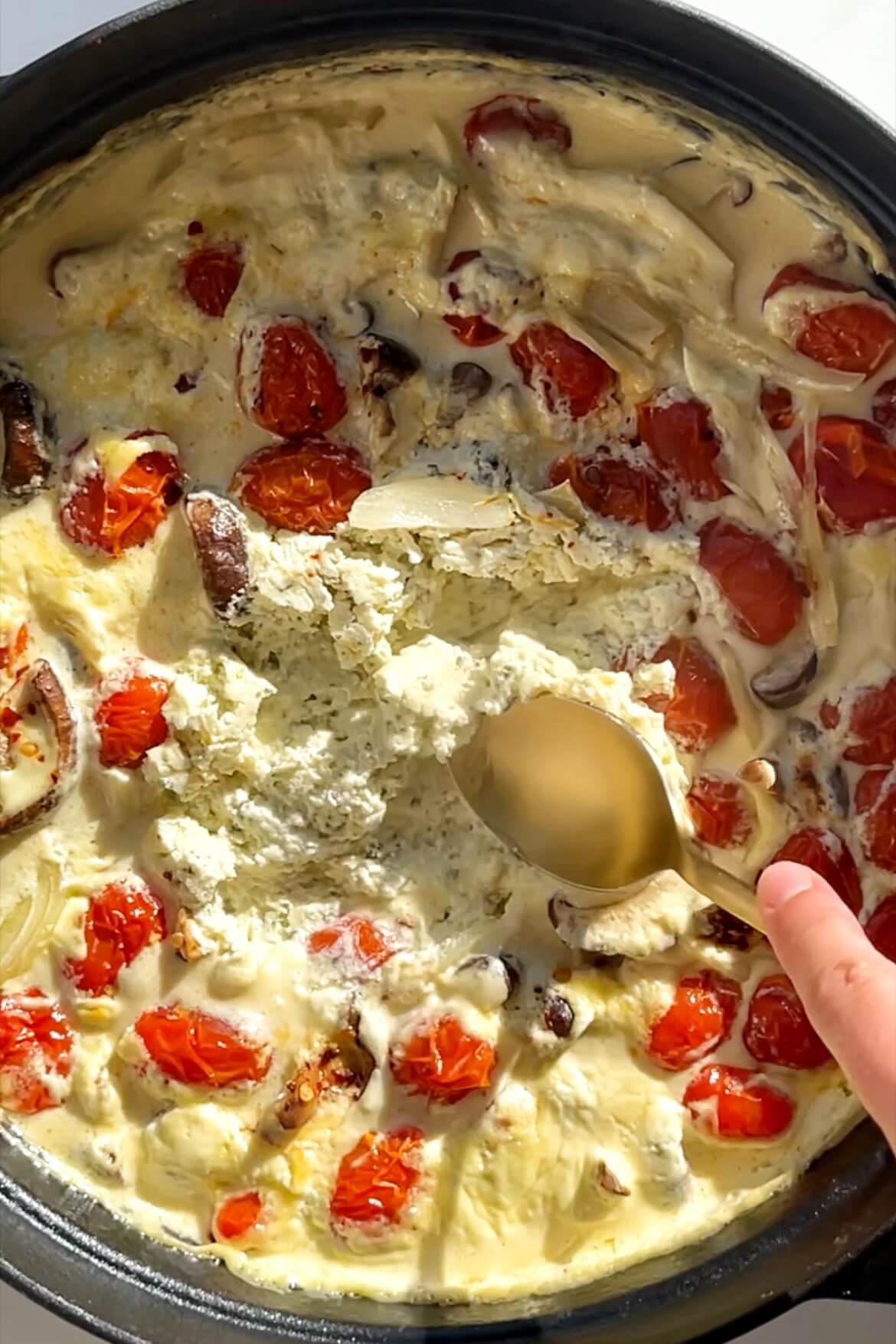 Black pan with Boursin pie filling in it with a golden spoon swooshing around in it.