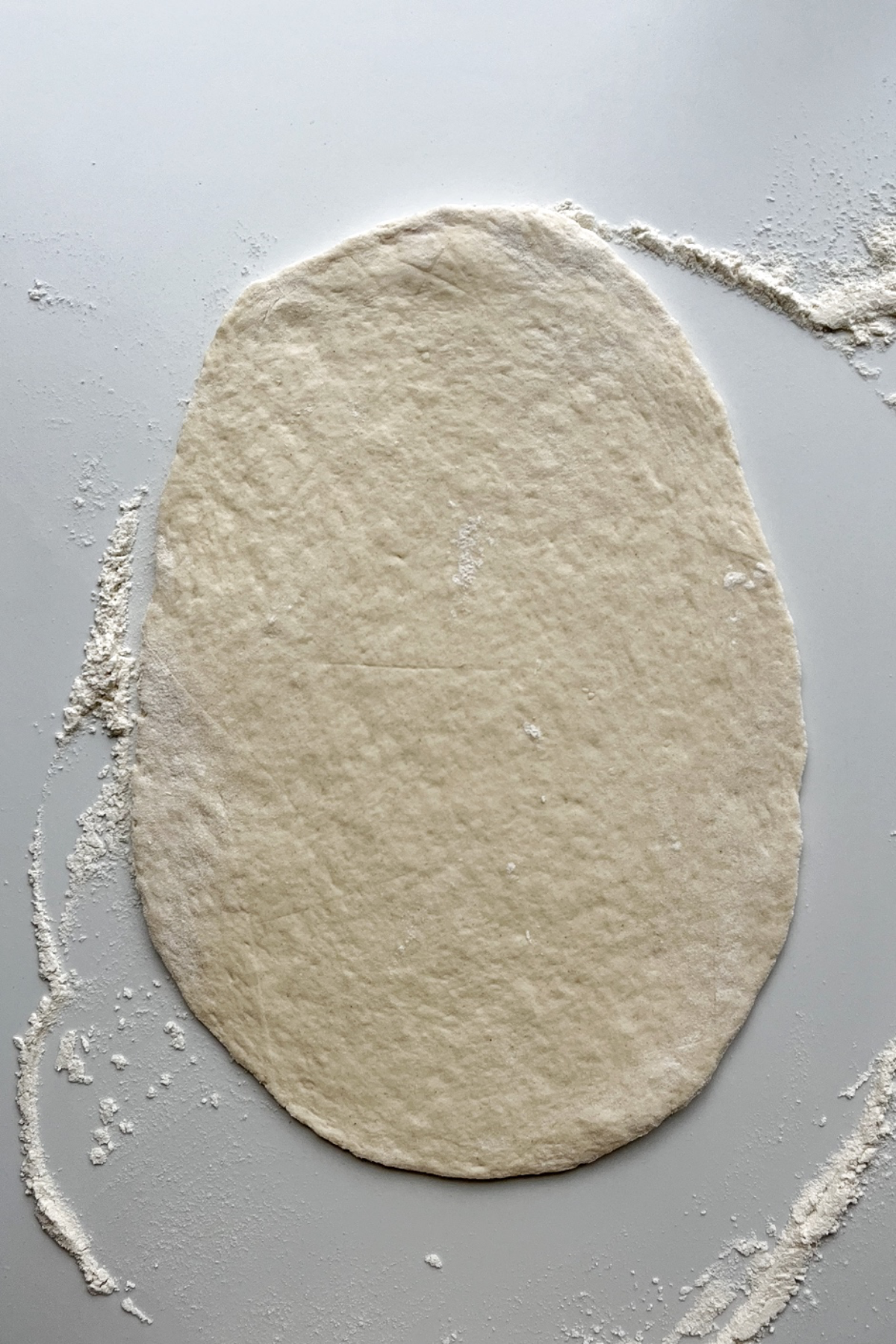 Rolled out piece of dough on white background.