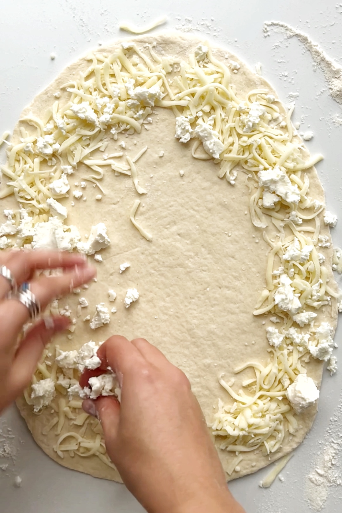 Large piece of rolled out dough with cheese on the outskirts of the dough.
