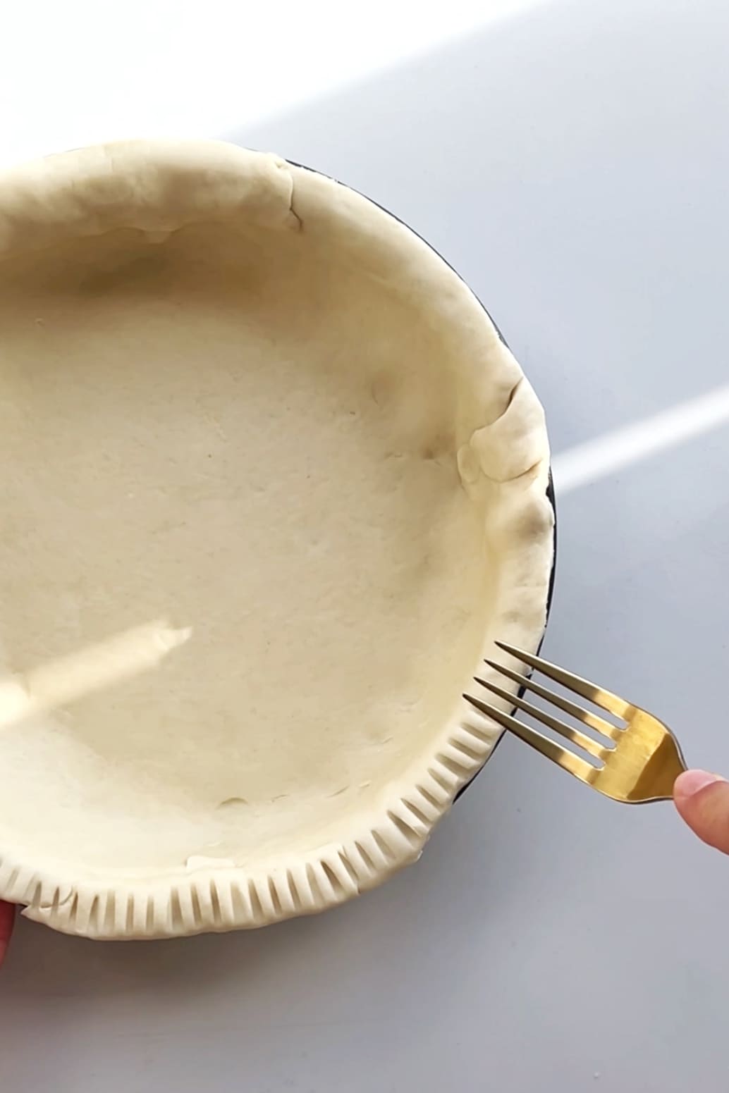 Pastry in tin, fork creating pattern.