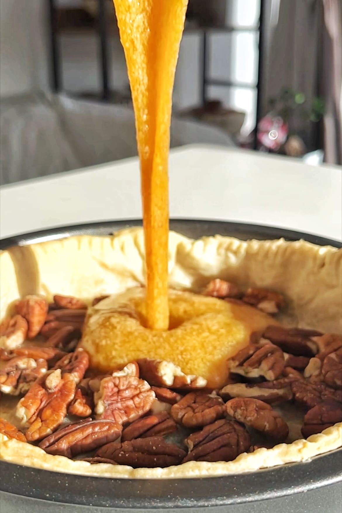Pouring sweet pecan pie filling into pie mixture.
