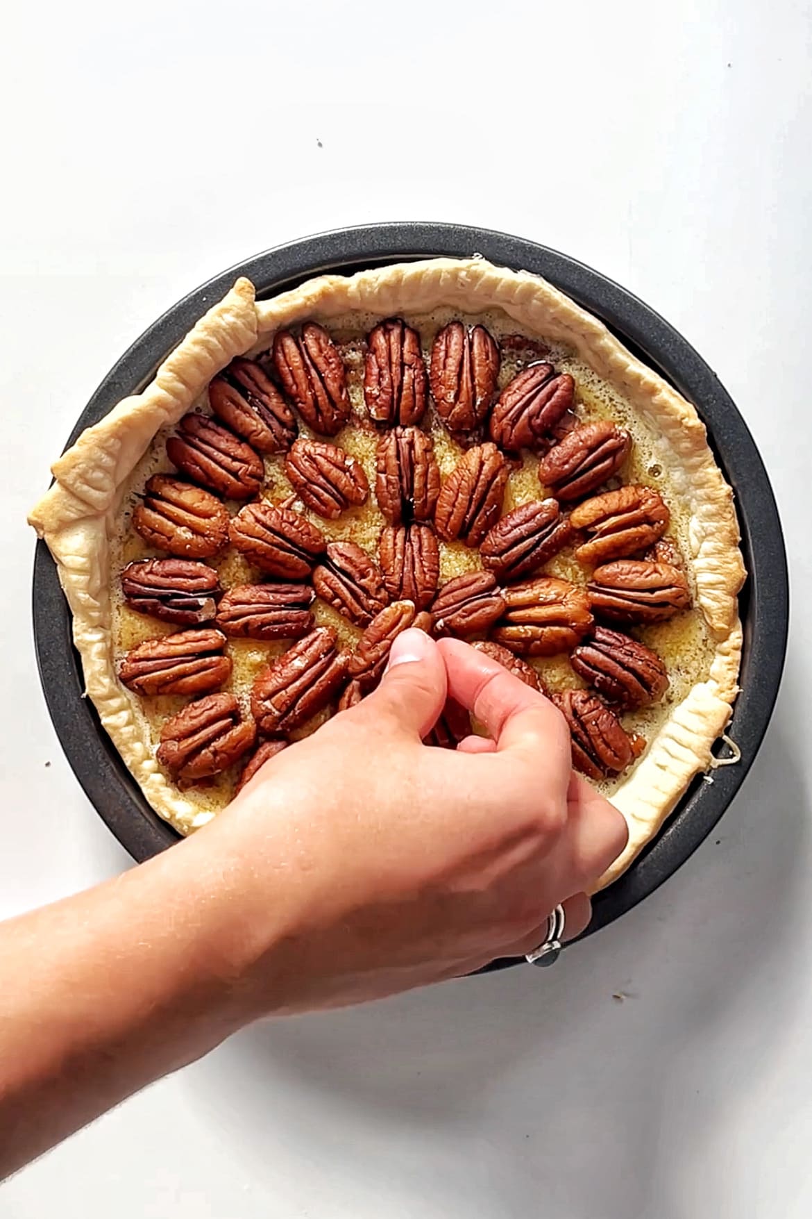 Placing pecans down onto a pie.