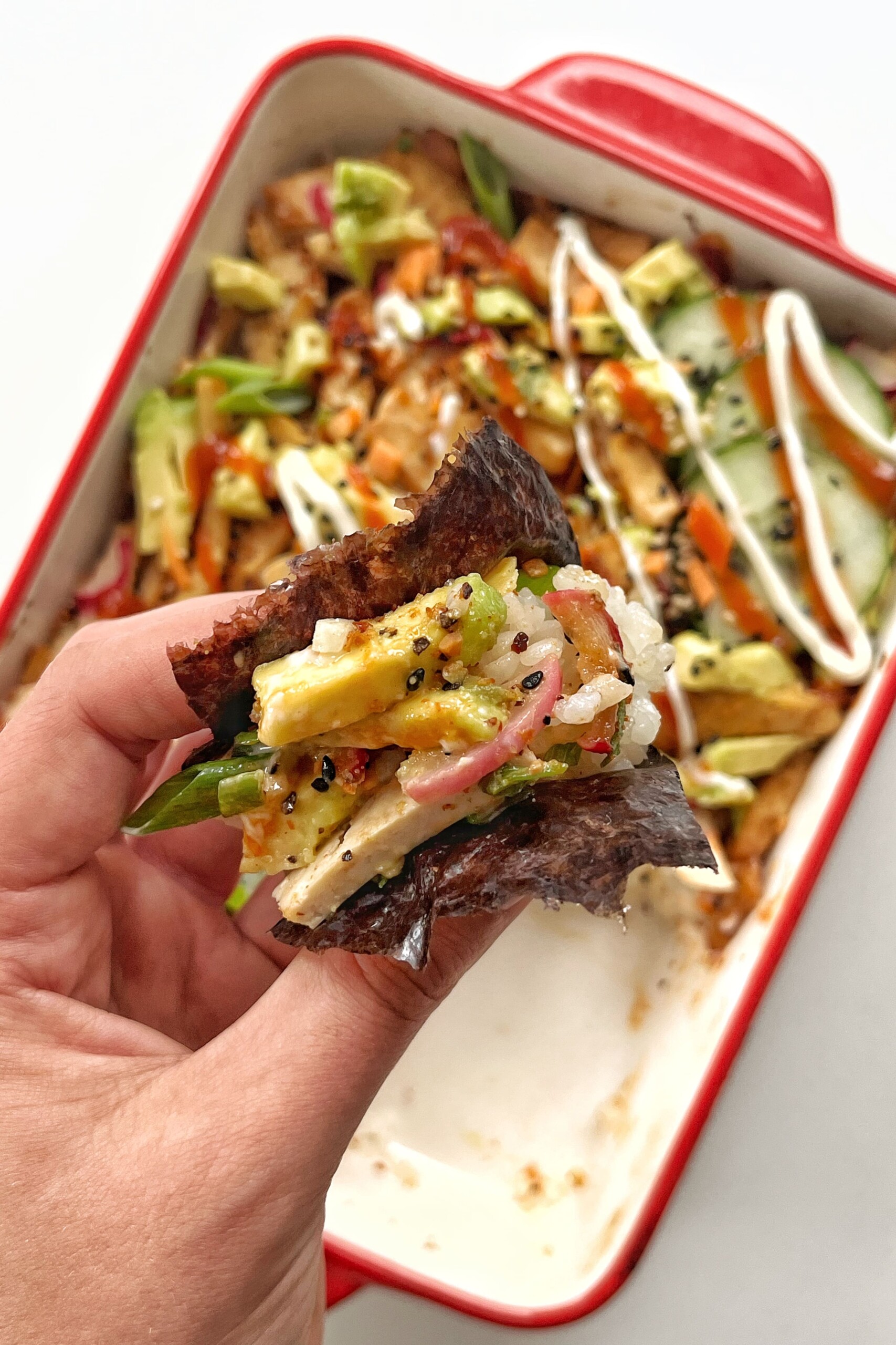 Picking up vegan sushi bake with nori sheet.