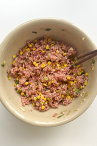 Dumpling filling in large bowl with chopsticks.