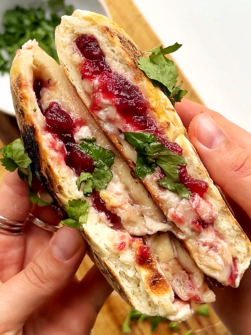 Opening of a festive turkey flatbread with cranberry sauce, brie, and turkey.