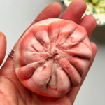 Pink and white dumpling held in lady's hand.