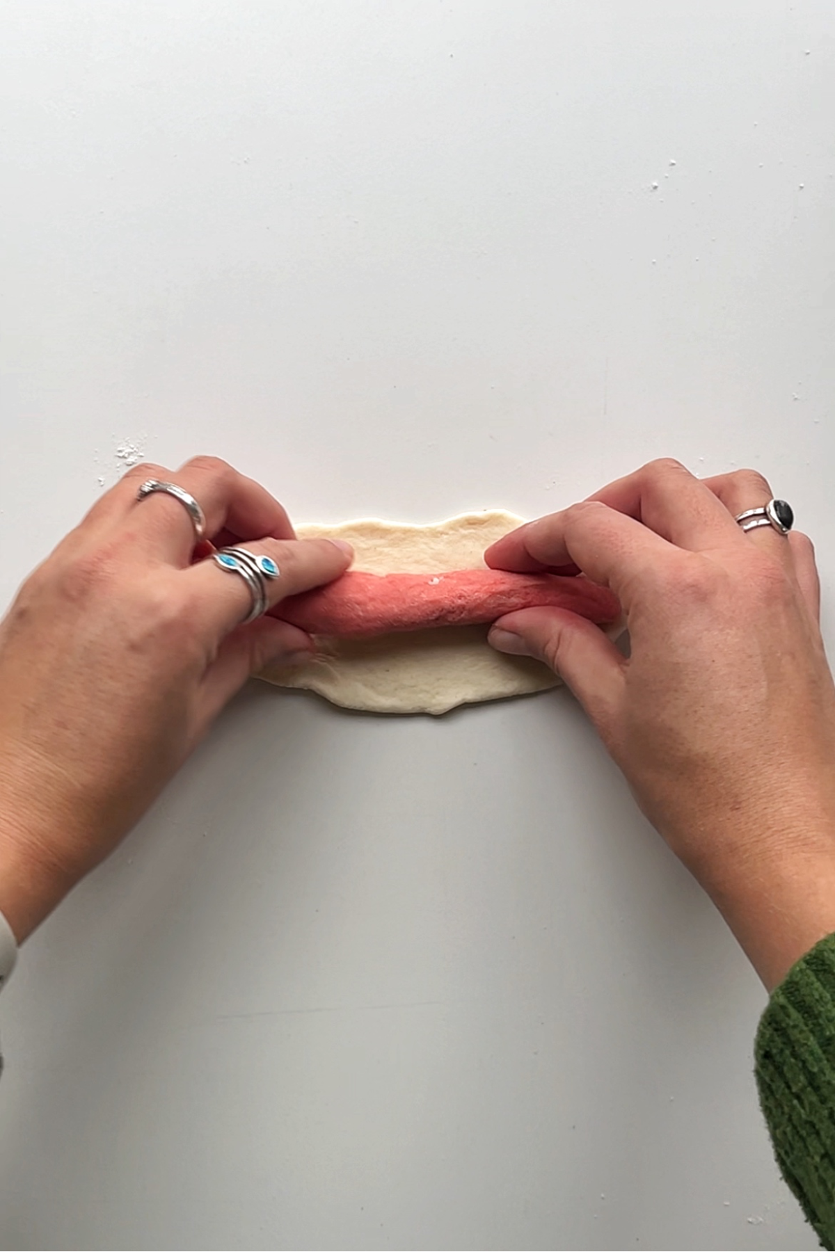 Placing pink log dough into the white piece of dough.