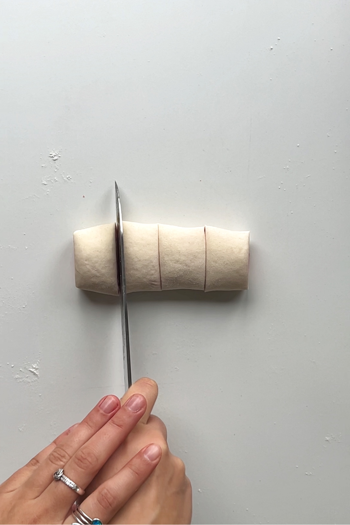 Slicing the roll of dough into 4 pieces.