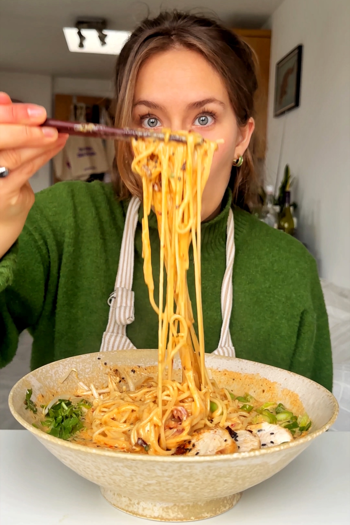Emily Roz lifting up noodles with chopsticks.