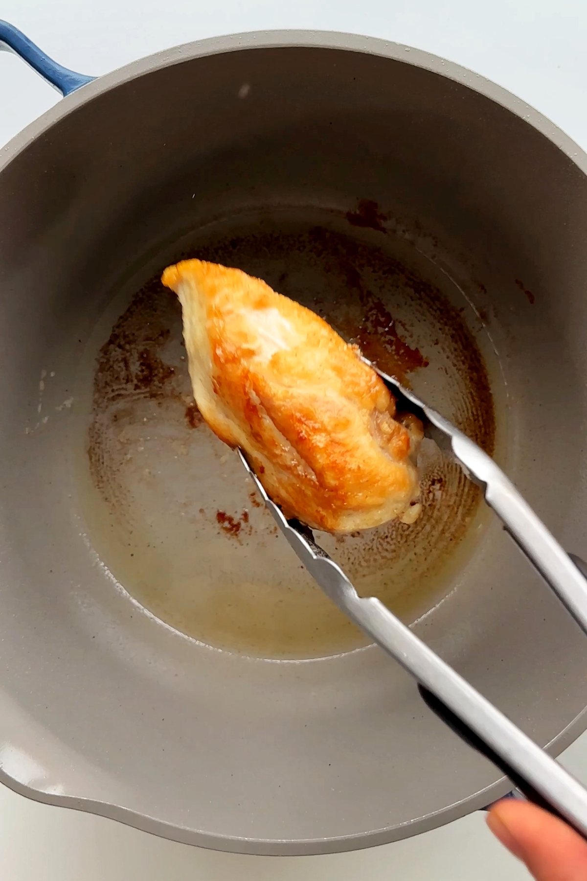 Fried chicken breast held by tweezers.