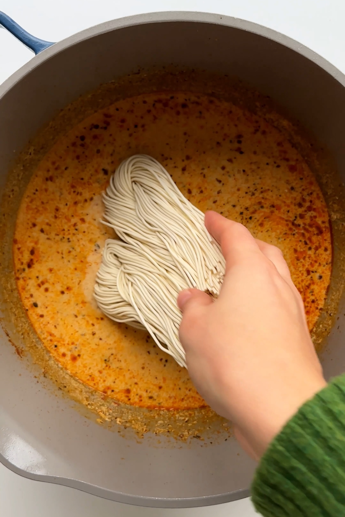 Placing ramen noodles into marry me chicken sauce in saucepan.