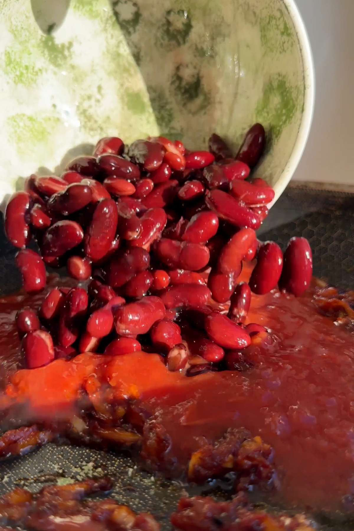 Pouring kidney beans into a tomato stew.