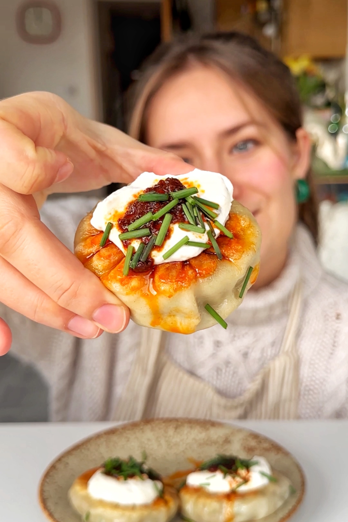 Emily Roz holding a beef spinach dumpling up to the camera.
