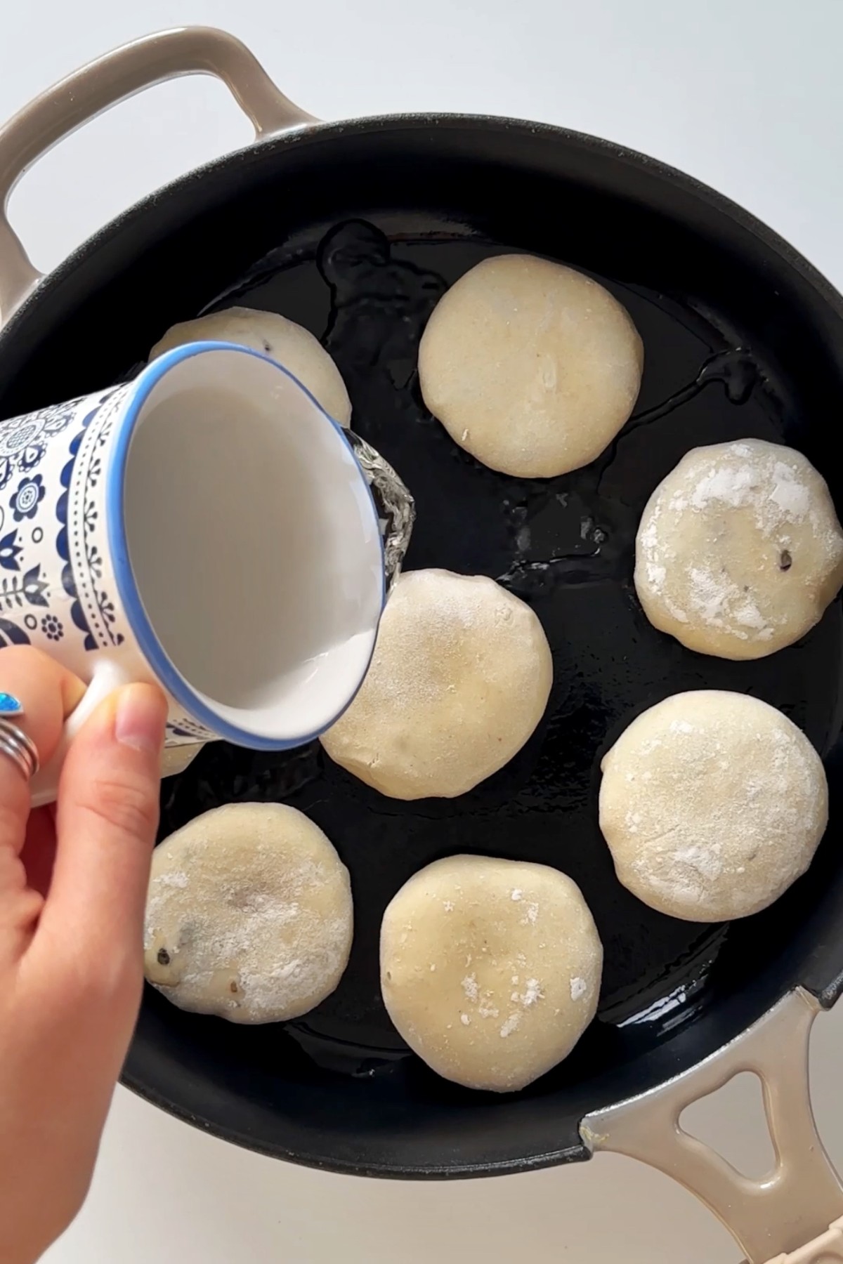 Pan-frying dumplings in black pan.