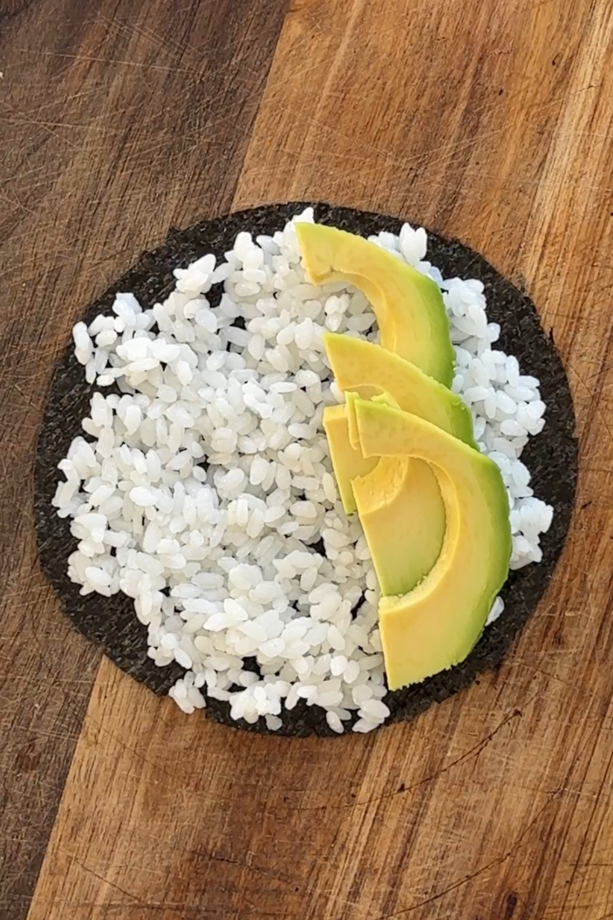 Round piece of nori topped with sushi rice and avocado.