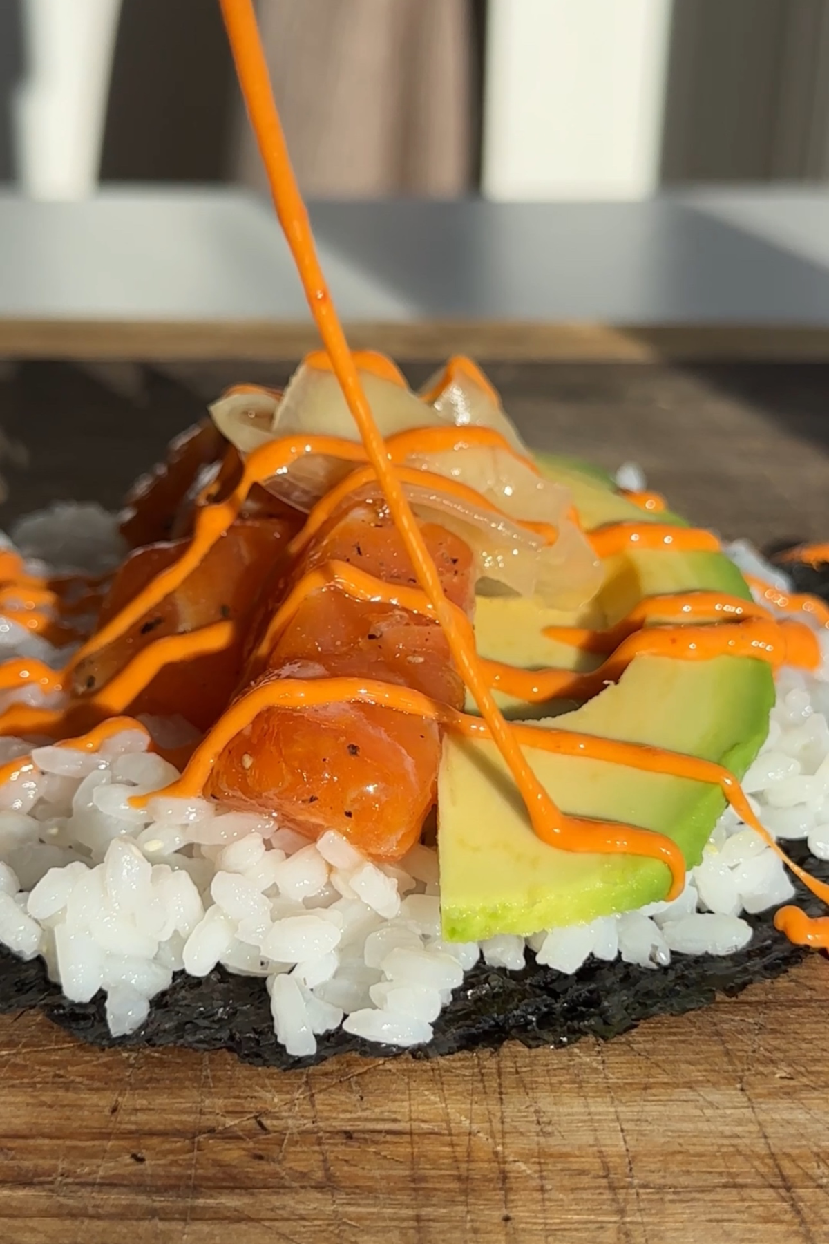 Sushi taco being drizzled over with sriracha mayonnaise.