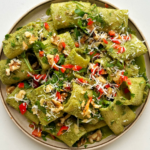 Zhoug-inspired rigatoni with walnuts, parsley, and chilli on a cream plate with a white background.