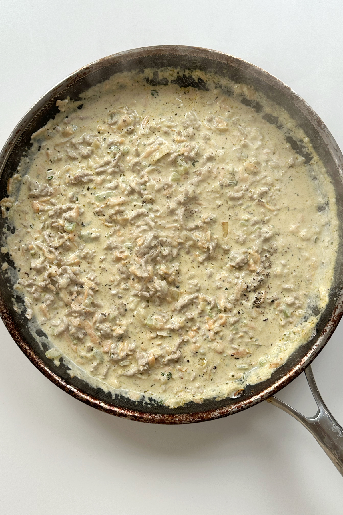 White ragu cooking in a black frying pan.
