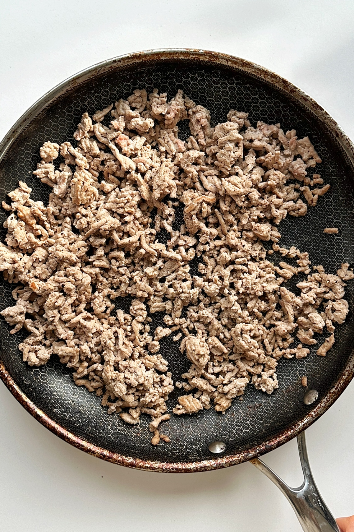 Ground turkey mince fried in a black frying pan.
