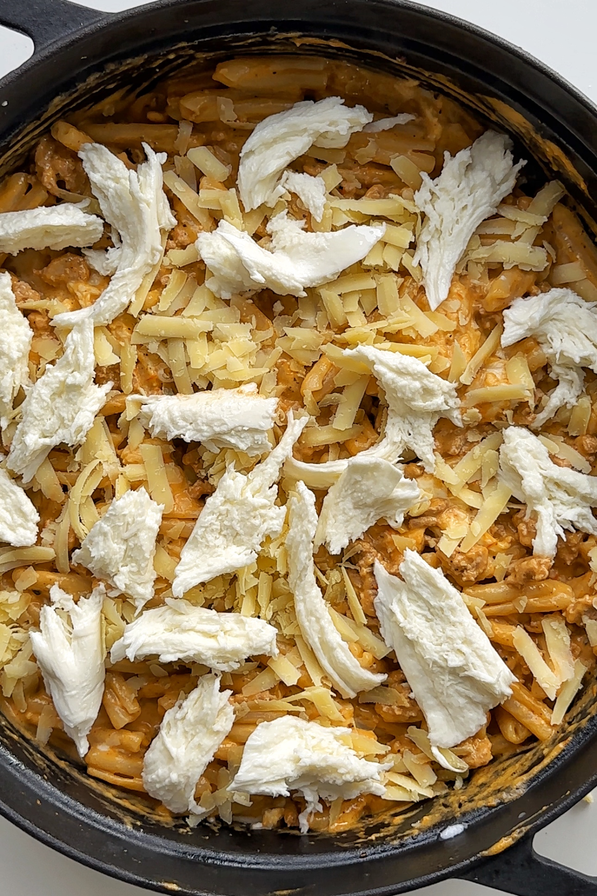 Pasta bake with mozzarella and cheddar cheese grated on top.