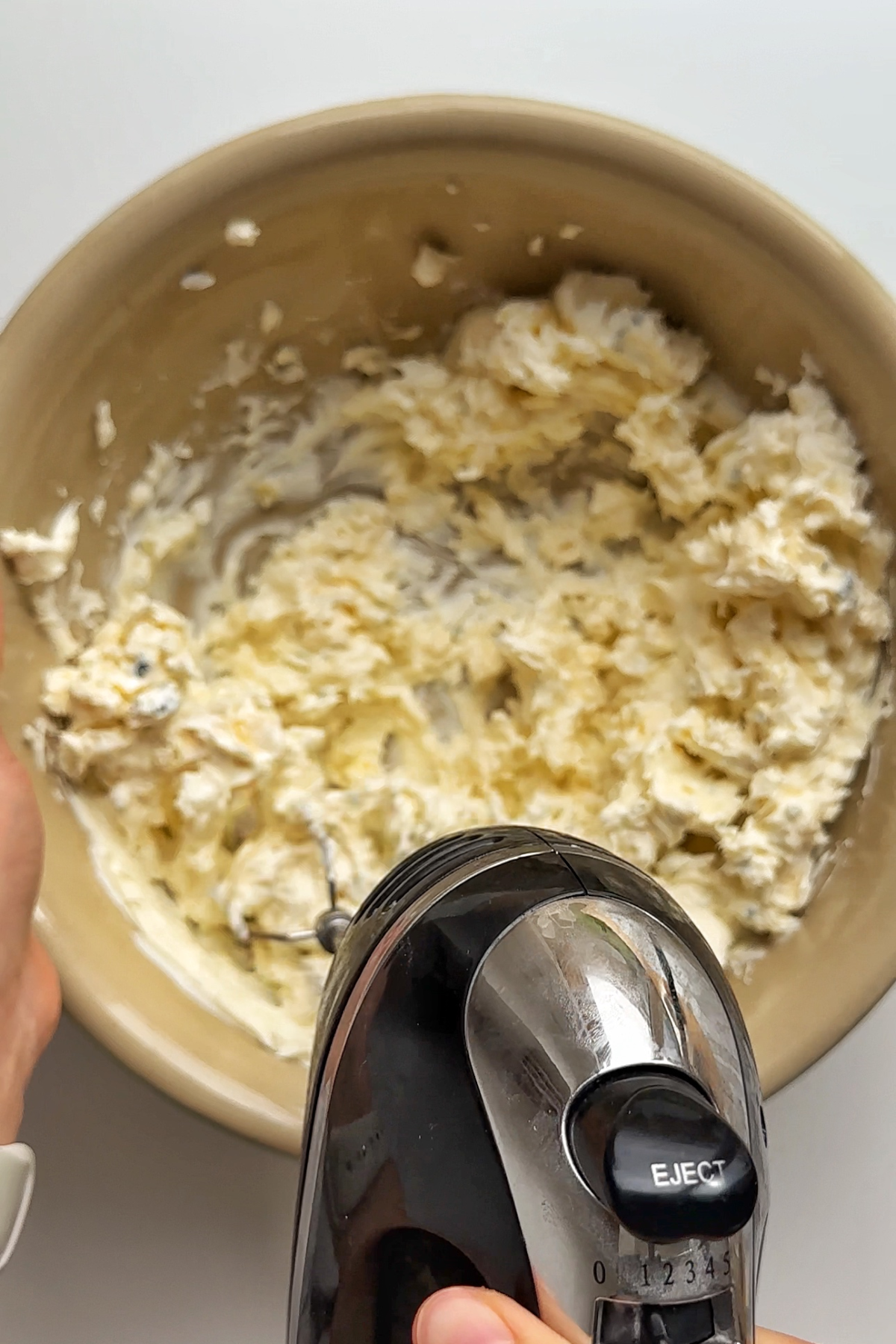 Whisking cheeses in bowl.