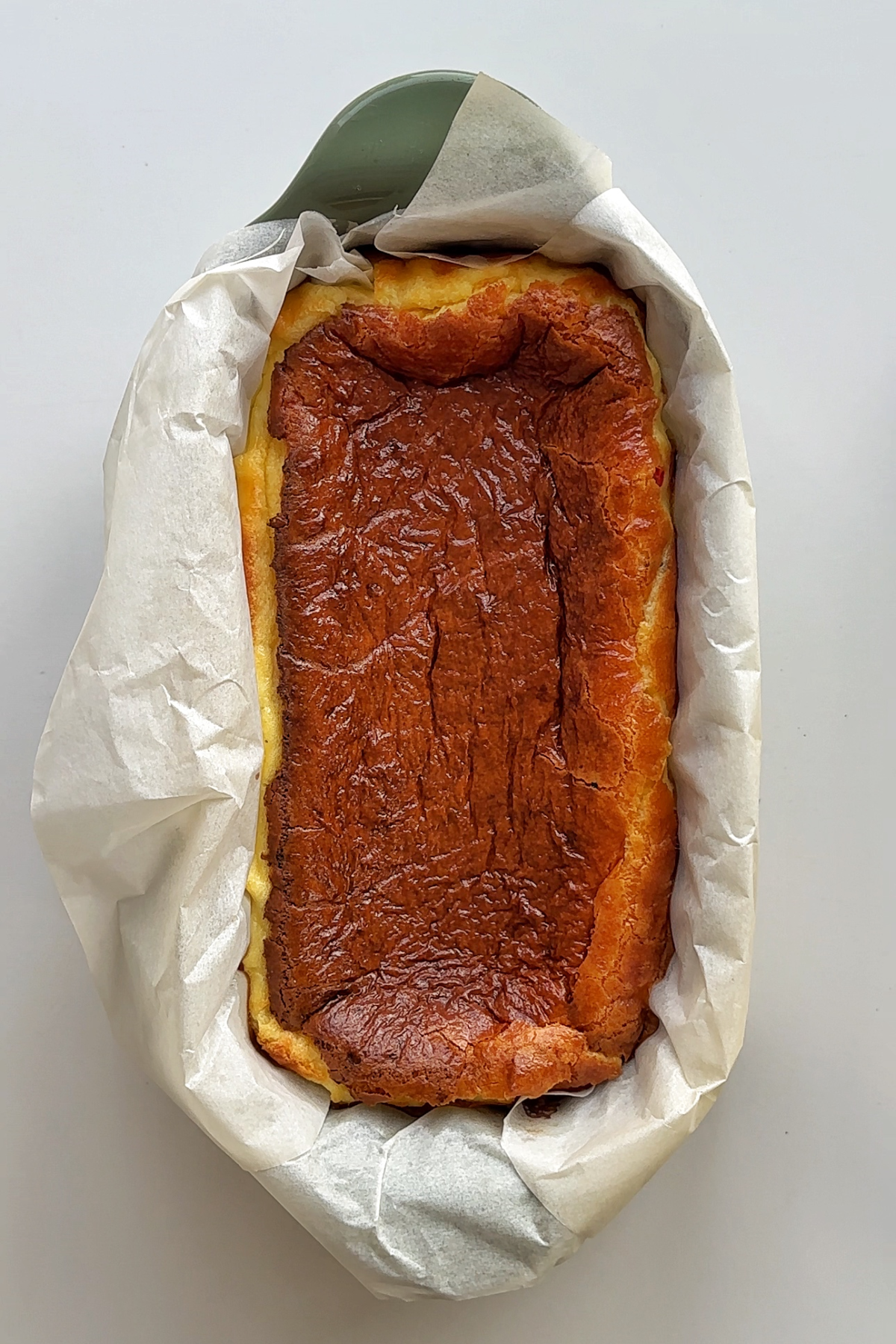 Baked burnt Basque savoury cheesecake on white surface.