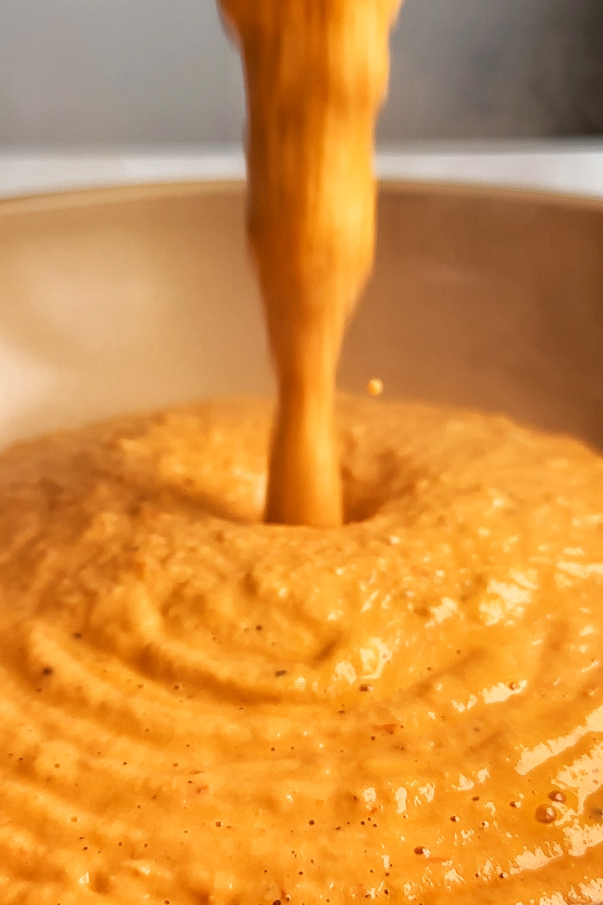 Pouring pasta sauce into a pan.