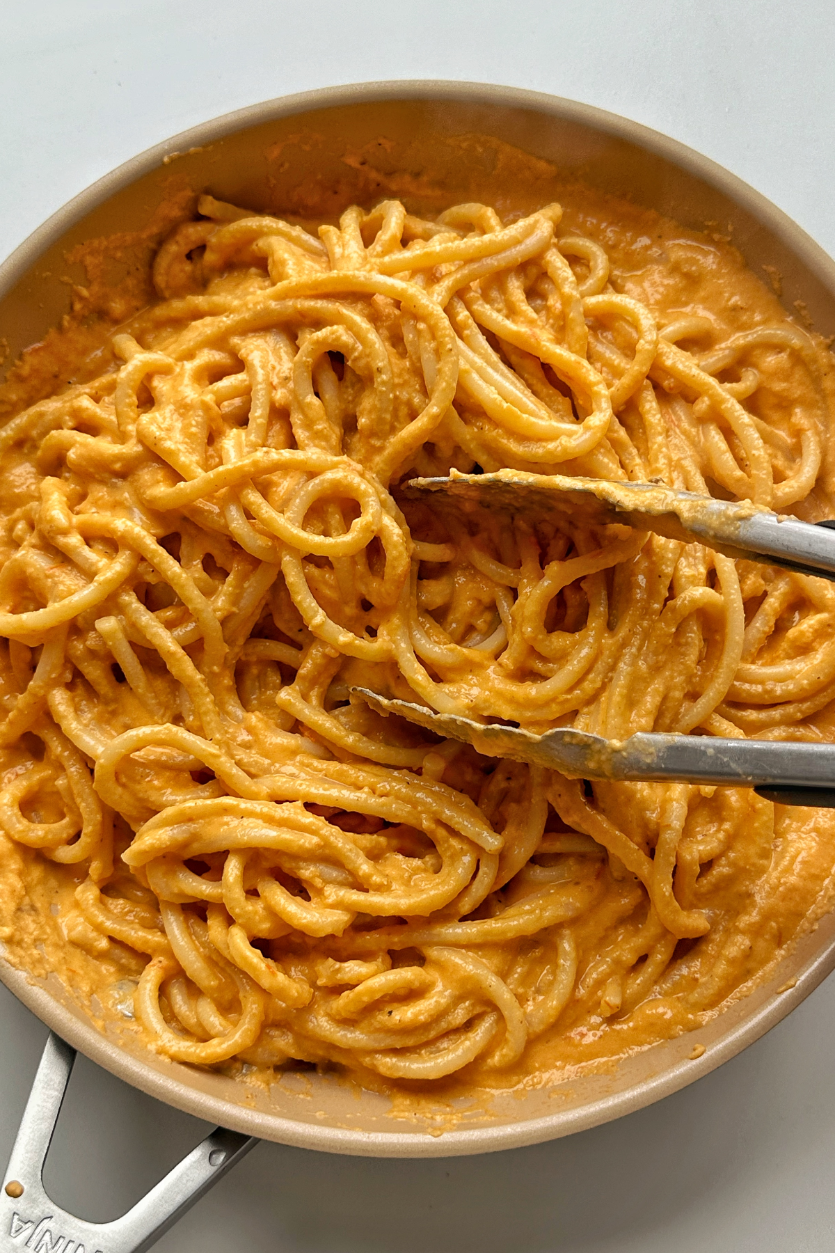 Combining pasta sauce with bucatini.