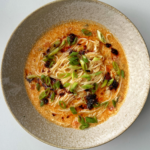 Bowl of noodles with tomato and egg drop.