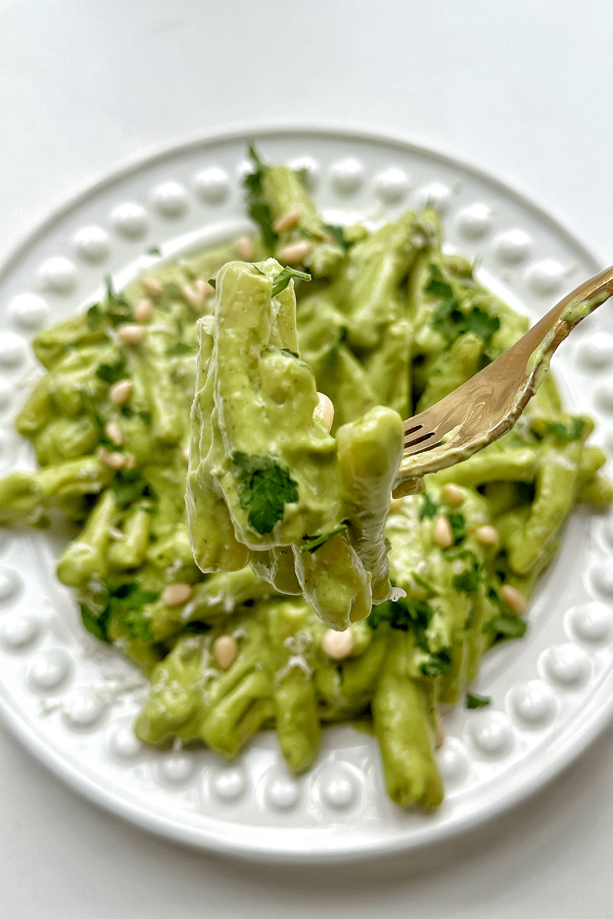 Close up of avocado pesto held up with a fork.
