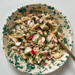 Bowl with chicken salad inside and a fork coming out of it.