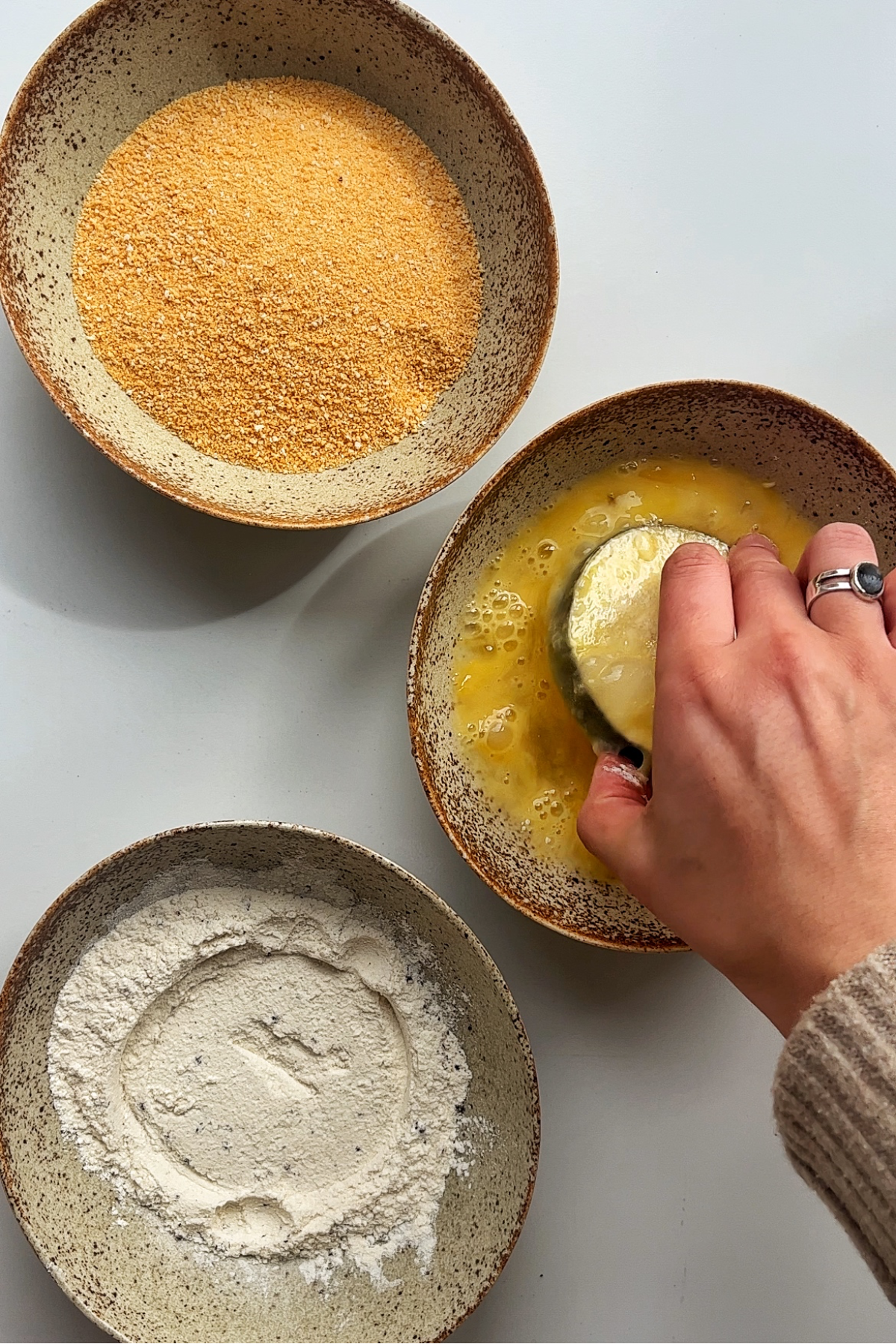 Coating aubergine discs in flour, egg, and panko breadcrumbs.