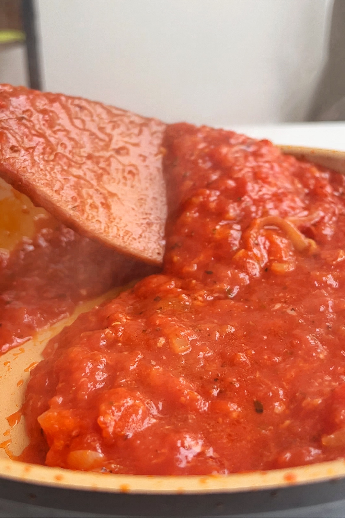 Stirring through a marinara sauce in a frying pan.